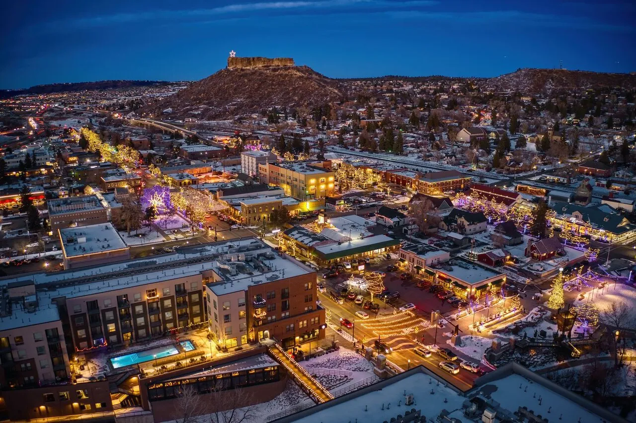 Downtown Castle Rock lit up at dusk with the town’s namesake rock on the horizon